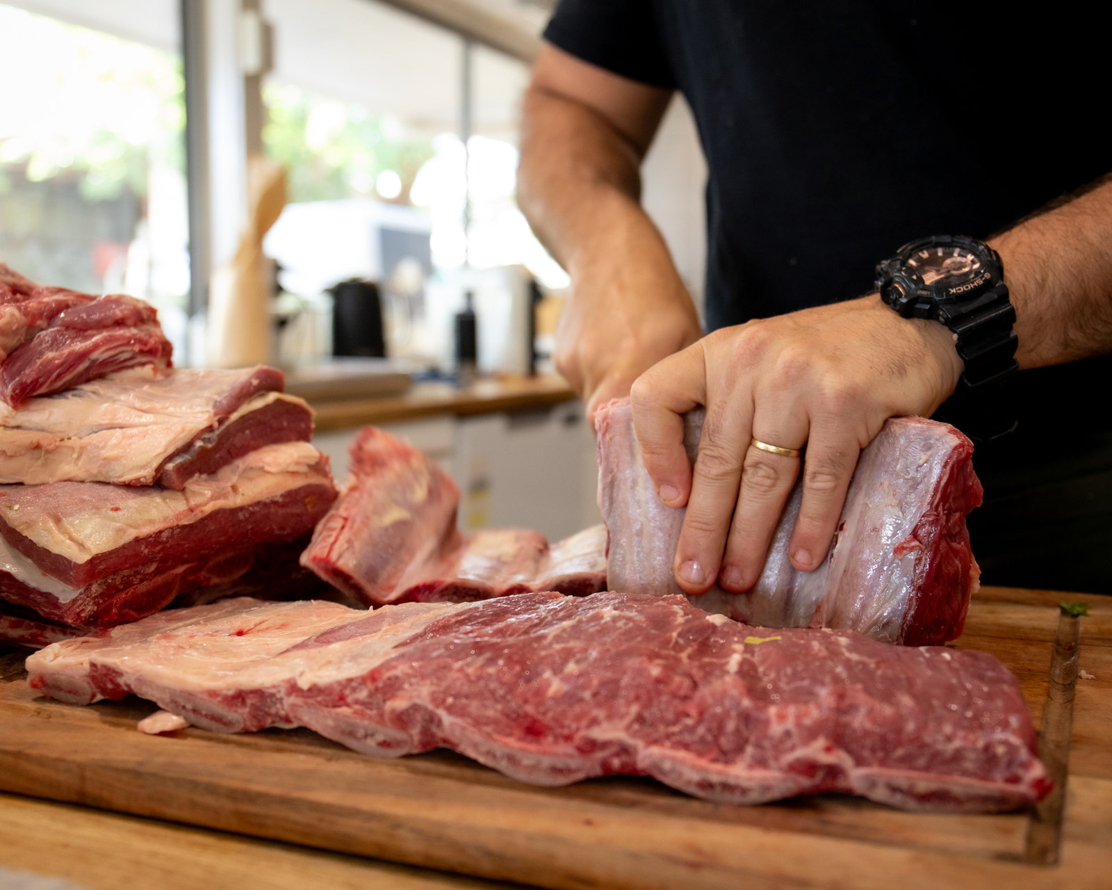 Hands preparing beef on a wooden butcher’s block.